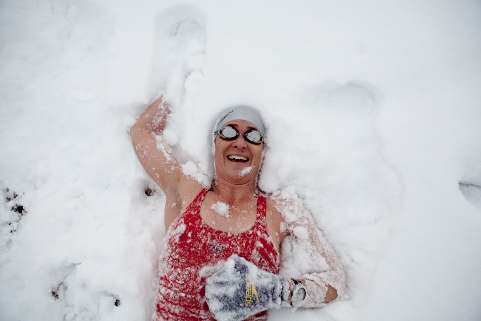 Swimmer lying in snow after a swim in the sea on Brighton beach