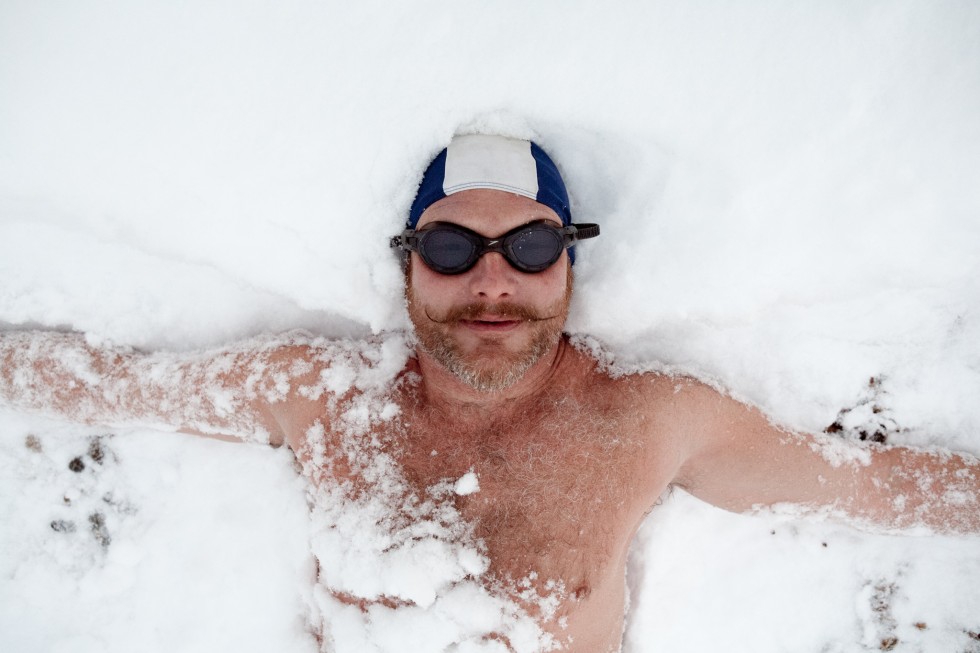 Swimmer lying in snow after a swim in the sea on Brighton beach
