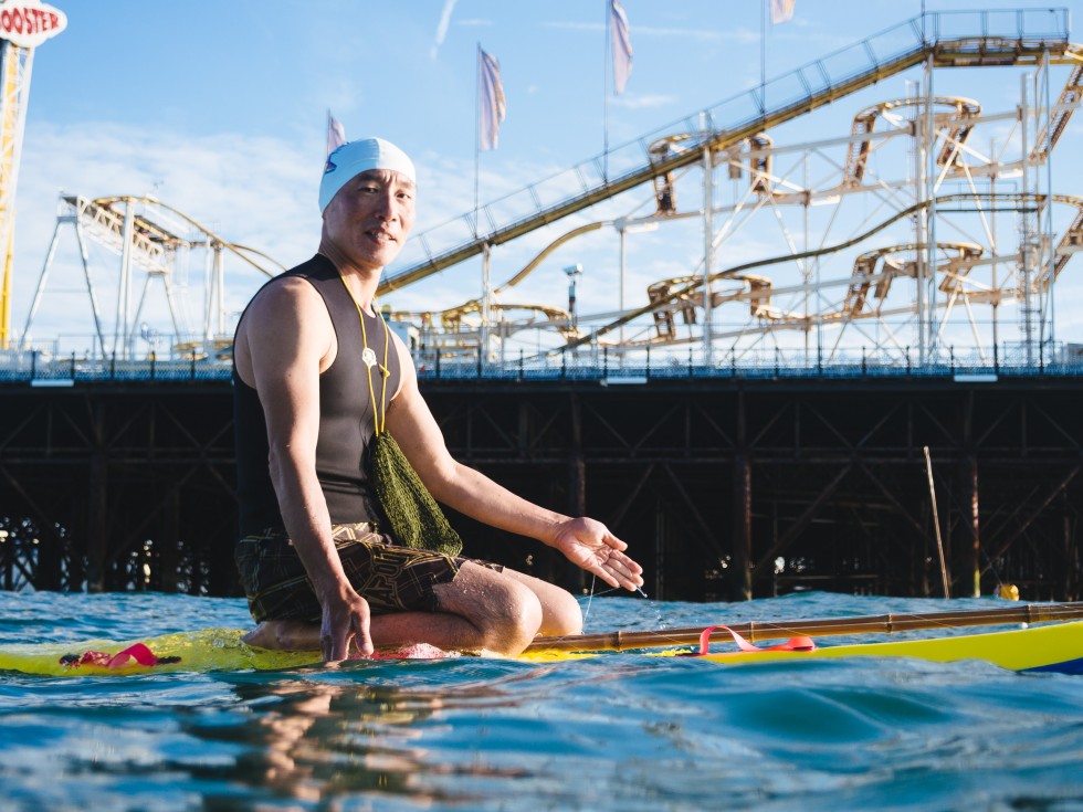 Shoichi fishing from a surfboard at the end of Brighton Pier